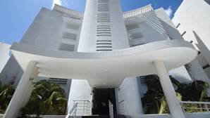Un bâtiment moderne doté d’une tour cylindrique centrale, d’une façade blanche et d’un espace d’entrée couvert accessible par un escalier.