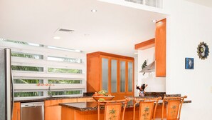 Une cuisine moderne avec un îlot central, des chaises en bois et un réfrigérateur.
