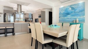 A modern kitchen with a central island, built-in appliances, and a dining area with a large painting.