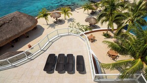 A resort balcony with a pool, lounge chairs, and palm trees.