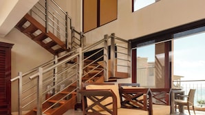 Ein großzügiger Innenraum mit Treppe, Holzmöbeln und großen Fenstern.