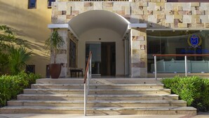 L'ingresso di un hotel con facciata in pietra, un balcone e un cartello con uno stemma.