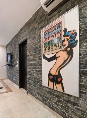 Un couloir avec un mur en pierre et une affiche encadrée de la pochette de l ’album « Squeeze » des Rolling Stones.