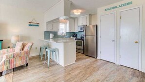 Una cocina compacta con una isla central, un refrigerador y un microondas.