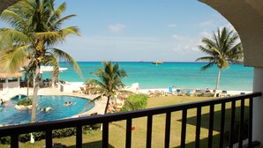 A pool area with palm trees, lounge chairs, and a view of the ocean. - Caribbean Views and Sparkling Pool! Xaman Ha 7103 (Playa del Carmen)