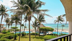 Un resort con piscina, palmeras y vista al océano.