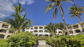 Un hotel de varios pisos con un patio central, rodeado de palmeras y abundante vegetación.
