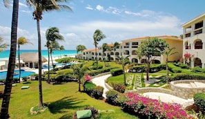 Een resort met een zwembad, palmbomen en uitzicht op de oceaan.
