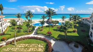 A resort with a pool, palm trees, and a view of the ocean.