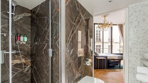 Ein modernes Badezimmer mit einer Glaskabine zur Dusche, Marmorwänden und einem sichtbaren WC.