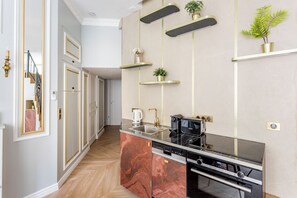 A modern kitchen with a marble island, stainless steel appliances, and gold accents. - Merveil - Luxury Suite - Louvre - Reaumur I (Paris)