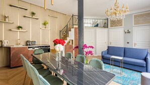 Eine moderne Küche mit Essbereich, einer Treppe und einem Wohnzimmer mit blauem Sofa.