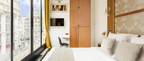 Una habitación de hotel con una cama grande, un escritorio, un televisor y un armario.