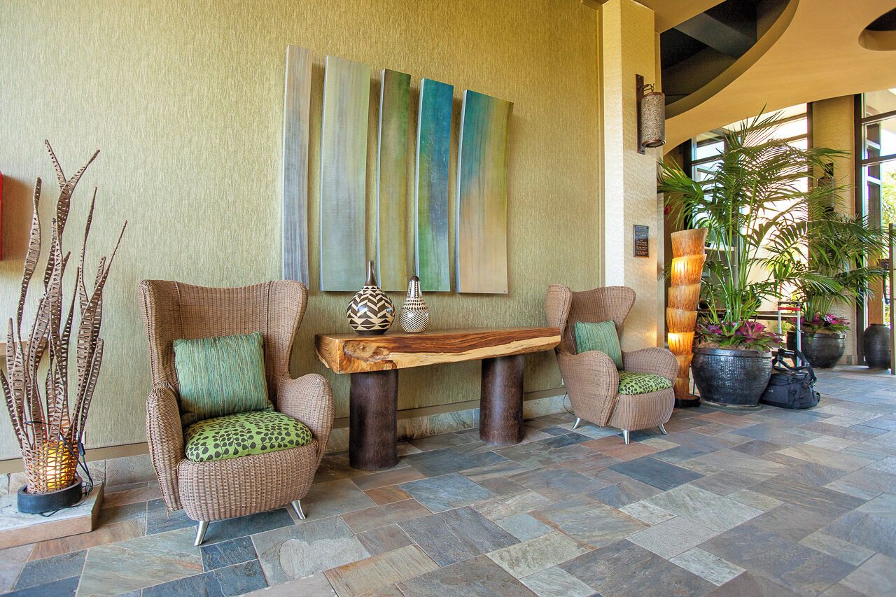 A lobby with wicker chairs, a wooden coffee table, and a large abstract painting on the wall.