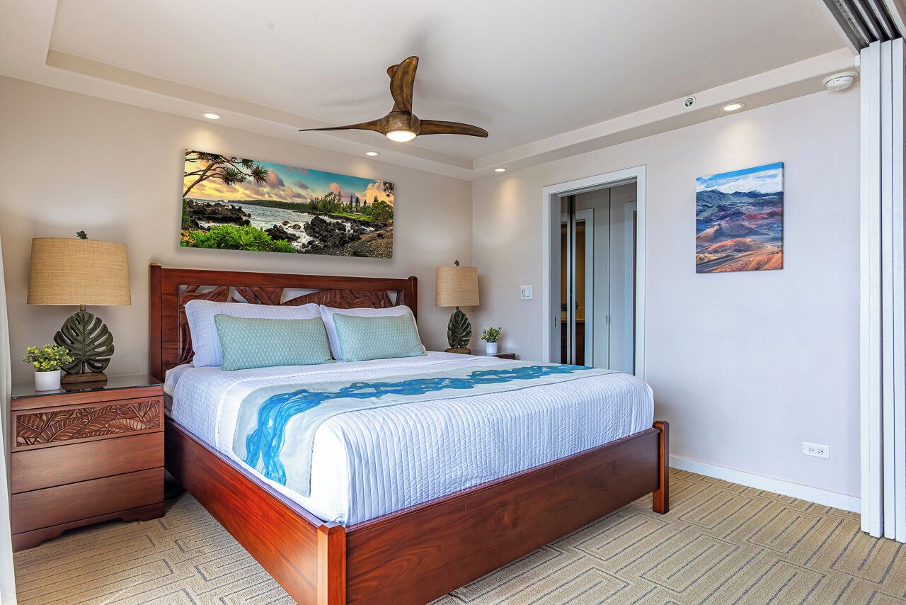 Une chambre à coucher avec un lit en bois, deux tables de chevet, un ventilateur de plafond et deux lampes fixées au mur.