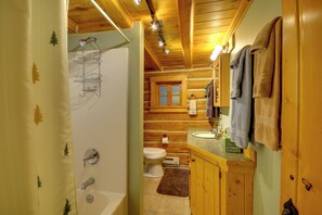 Ein Badezimmer einer Holzhütte mit Dusche, Toilette und Waschbecken.