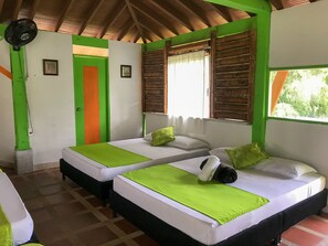 A room with two beds, each with a green bedspread, a window with wooden shutters, and a ceiling fan. - LAKE VIEW CABIN (Pereira)