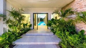 A modern building with a pool, surrounded by lush greenery and a covered walkway. - Ultra Modern Villa with Chef & Maid (Punta Cana)