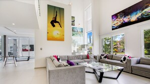 A spacious living room with a large gray sofa, a glass coffee table, and a modern chandelier. - Ultra Modern Villa with Chef & Maid (Punta Cana)