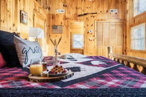 Um quarto de madeira acolhedor com uma cama, um edredom, um tabuleiro com waffles e frutas, e uma bandeira na parede.