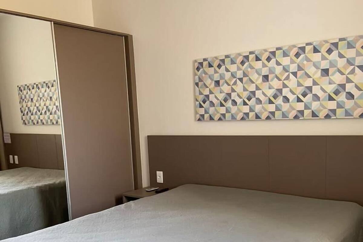 A hotel room with a large bed, a mirror, and a geometric-patterned wall art.