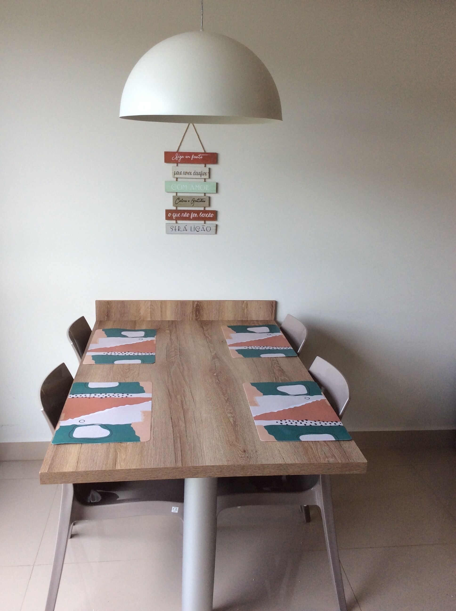 A conference table with a white pendant lamp above it, surrounded by chairs.