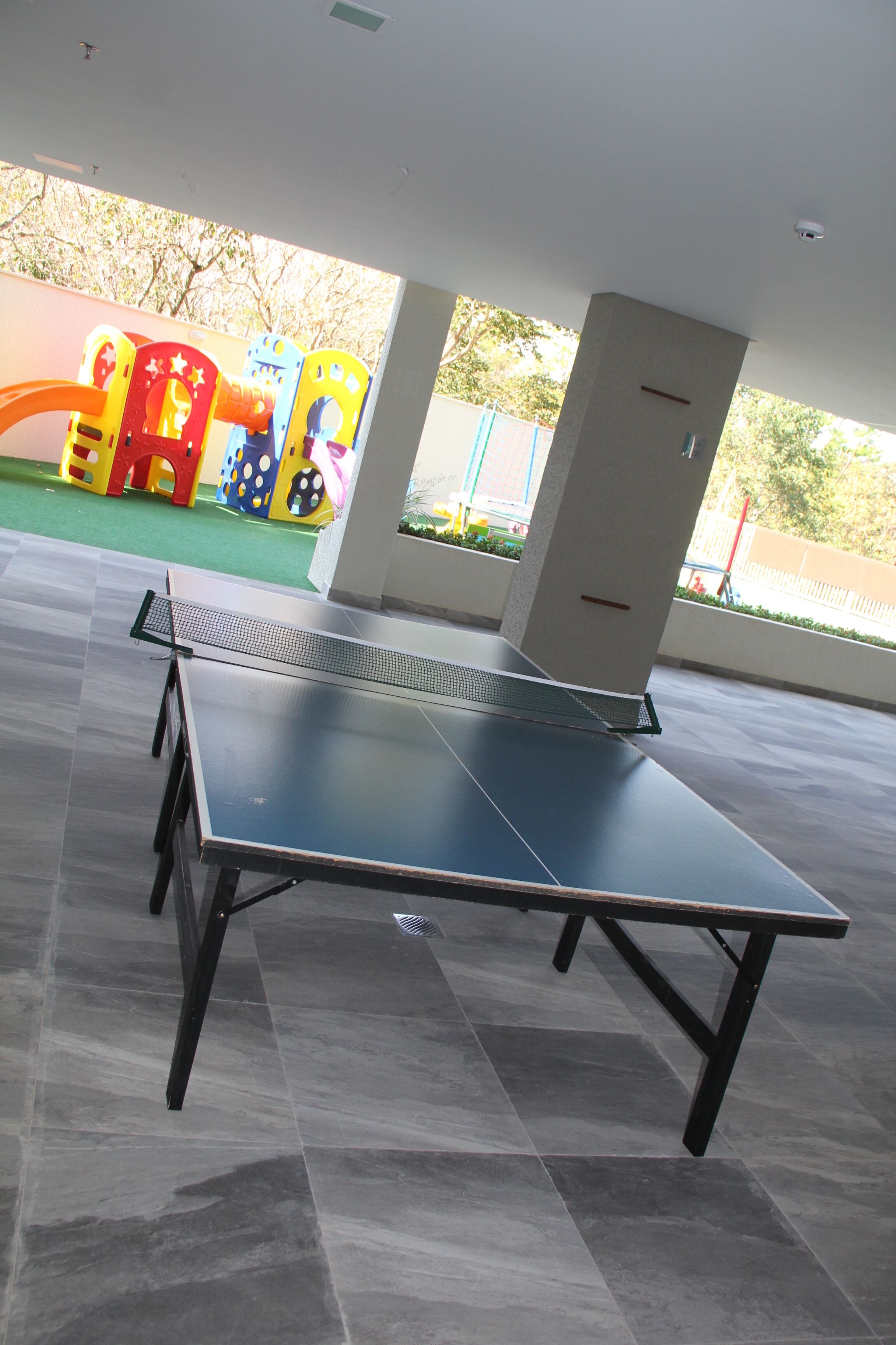 A ping pong table in a spacious indoor area with a tiled floor.