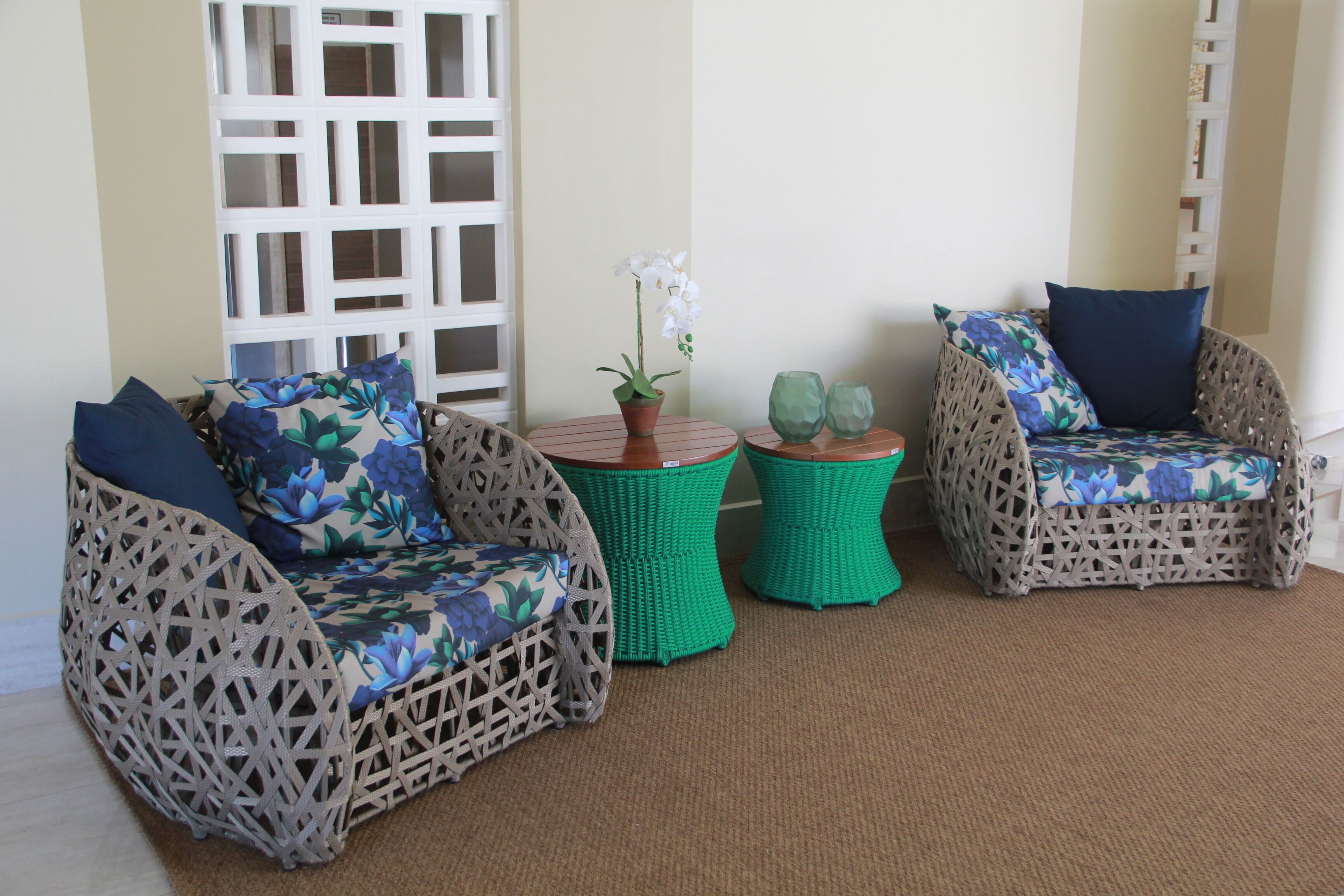 A seating area with wicker chairs and a small table, a potted orchid, and a decorative glass.