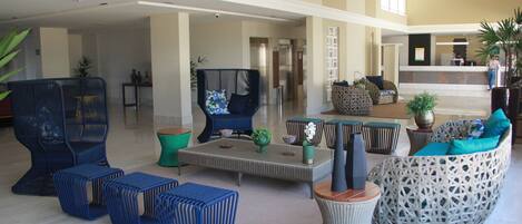 A spacious lobby with a high ceiling, a reception desk, and a variety of seating options including sofas and chairs.