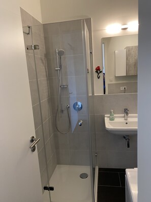 Een bad/douchecombinatie, handdoeken, zeep, toiletpapier