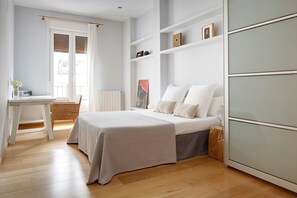 A bedroom with a bed, a desk, and shelves.