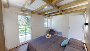 A bedroom with a large bed, a chair, a window, and a door. - 2 gites in a green setting (Sainte-Marie-de-Ré)