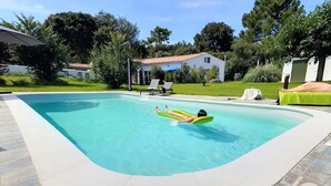 A swimming pool with a person floating on an inflatable ring. - 2 gites in a green setting (Sainte-Marie-de-Ré)