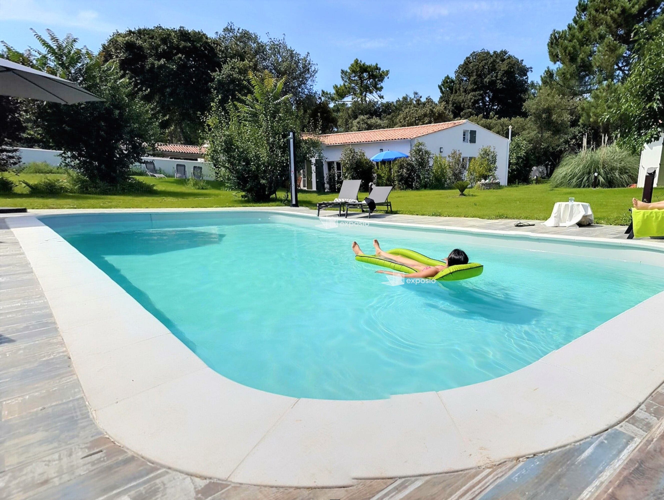 A swimming pool with a person floating on an inflatable ring.