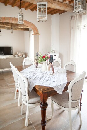 A dining area with a wooden table, white chairs, and a white lace tablecloth. - BEAUTIFUL HOUSE BETWEEN PISA AND FLORENCE WITH PRIVATE POOL (Toscana)