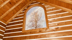A wooden interior with a sloped ceiling and a window framed by a wooden arch. - Come to "LOG OUT" and have fun! (Pinnacle)