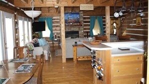 A rustic cabin interior with a wooden dining table, a sofa, a fireplace, and a wine rack. - Come to "LOG OUT" and have fun! (Pinnacle)