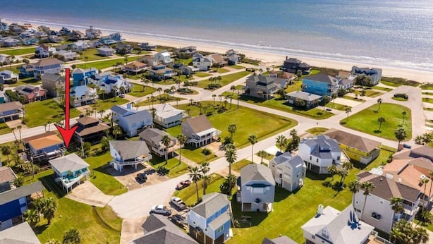 Vista aérea de una zona residencial costera con casas, calles y una playa.