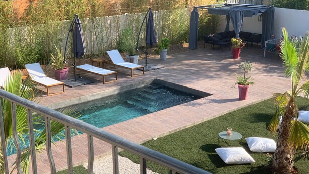 A backyard with a swimming pool, lounge chairs, a covered seating area, and potted plants. - Studio for 4 people (Les Arcs)