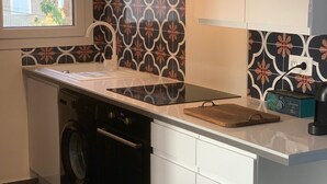 A compact kitchen with a washing machine, a coffee maker, and a wooden cutting board on the counter. - Studio for 4 people (Les Arcs)