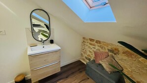 A bedroom with a skylight, a wooden floor, a stone headboard, and a bedside table with a lamp. - Studio for 4 people (Les Arcs)