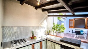 Una cocina con estufa a gas, un lavamanos y un pequeño comedor con mesa y sillas.