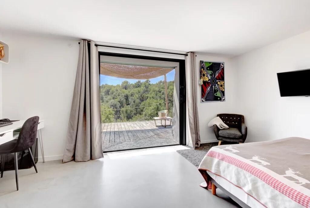 Un dormitorio con una cama grande, un escritorio, una silla y vistas a un balcón con mesa y sillas.