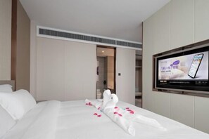 Ein Hotelzimmer mit einem Bett, einem Fernseher und einer Tür zu einem anderen Raum.