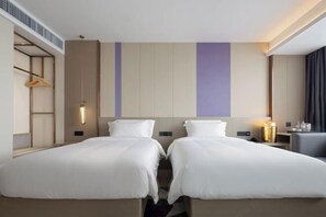 A hotel room with two beds, a bedside table with a lamp, a wardrobe, and a hanging coat rack. - Lavande Hotel (Zhuhai Qinglv North Road Tangjiawan Beach) (Zhuhai)