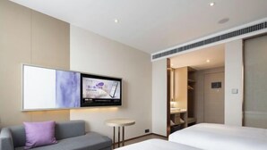 Una camera d'albergo con un letto, una poltrona, una TV a parete e un tavolino.