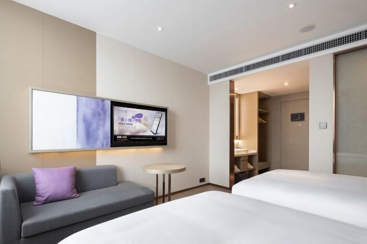A hotel room with a bed, a sofa, a TV, and a small table.