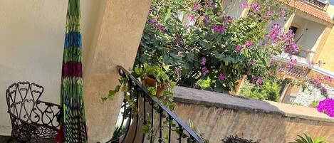 A balcony with a hammock, a chair, and potted plants.