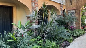 A building with a brick facade, arched doorways, and a balcony with potted plants. - Mesón de las Delicias (Cuernavaca)