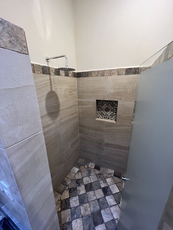 A small, tiled shower area with a sink and a decorative tile pattern on the wall. - Mesón de las Delicias (Cuernavaca)